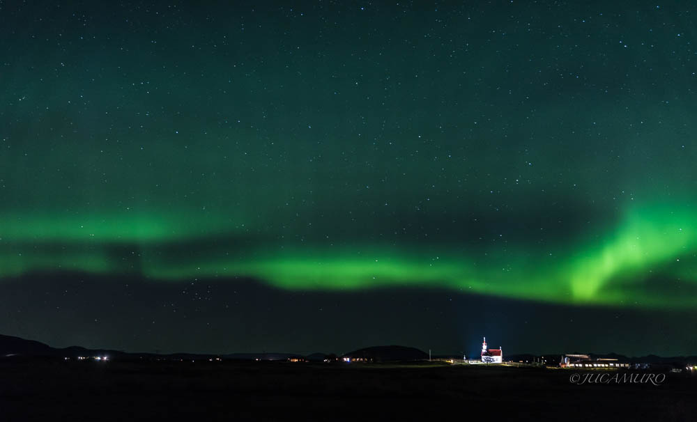 Aurora boreal. Iglesia y cementerio rural iluminados.