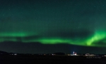 Aurora boreal. Iglesia y cementerio rural iluminados.